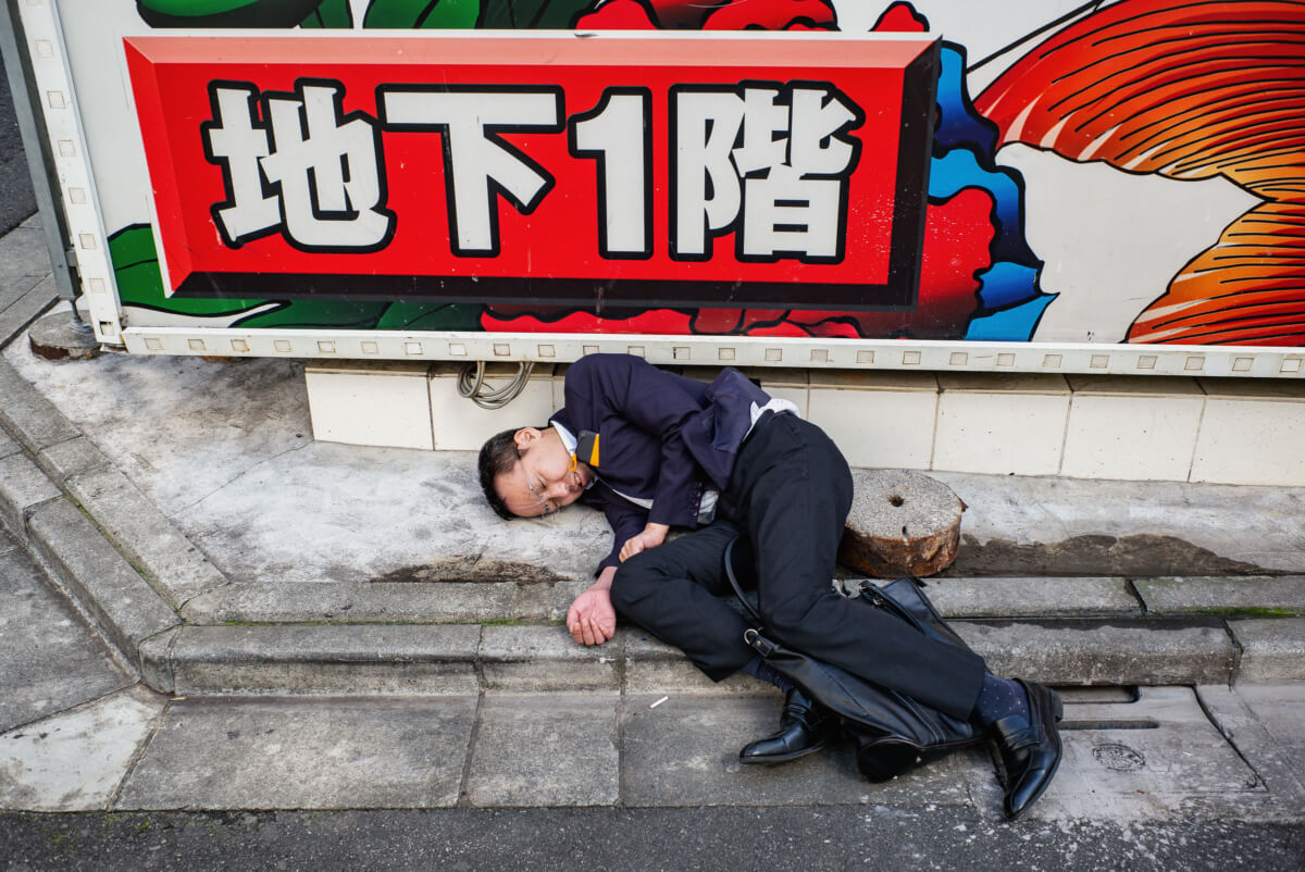 A Japanese salary man drunk and asleep on the street