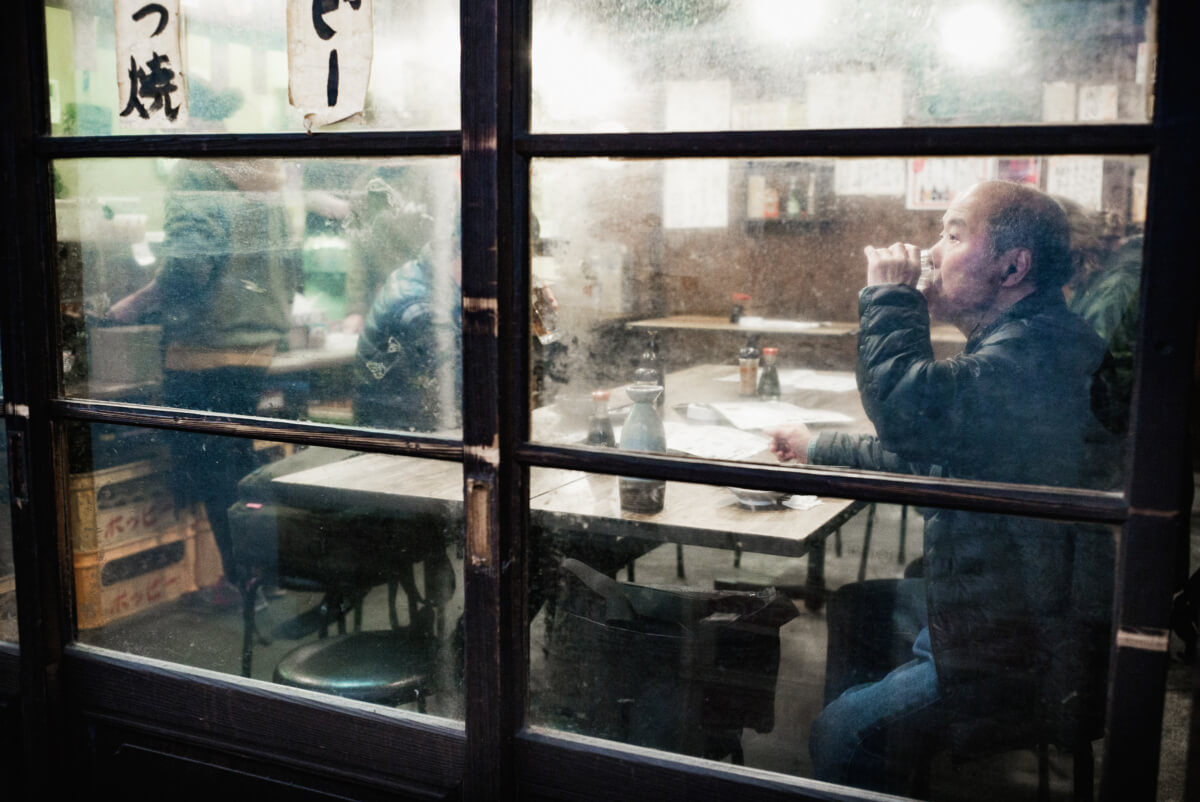 an atmospheric Tokyo bar and a Japanese man drinking sake