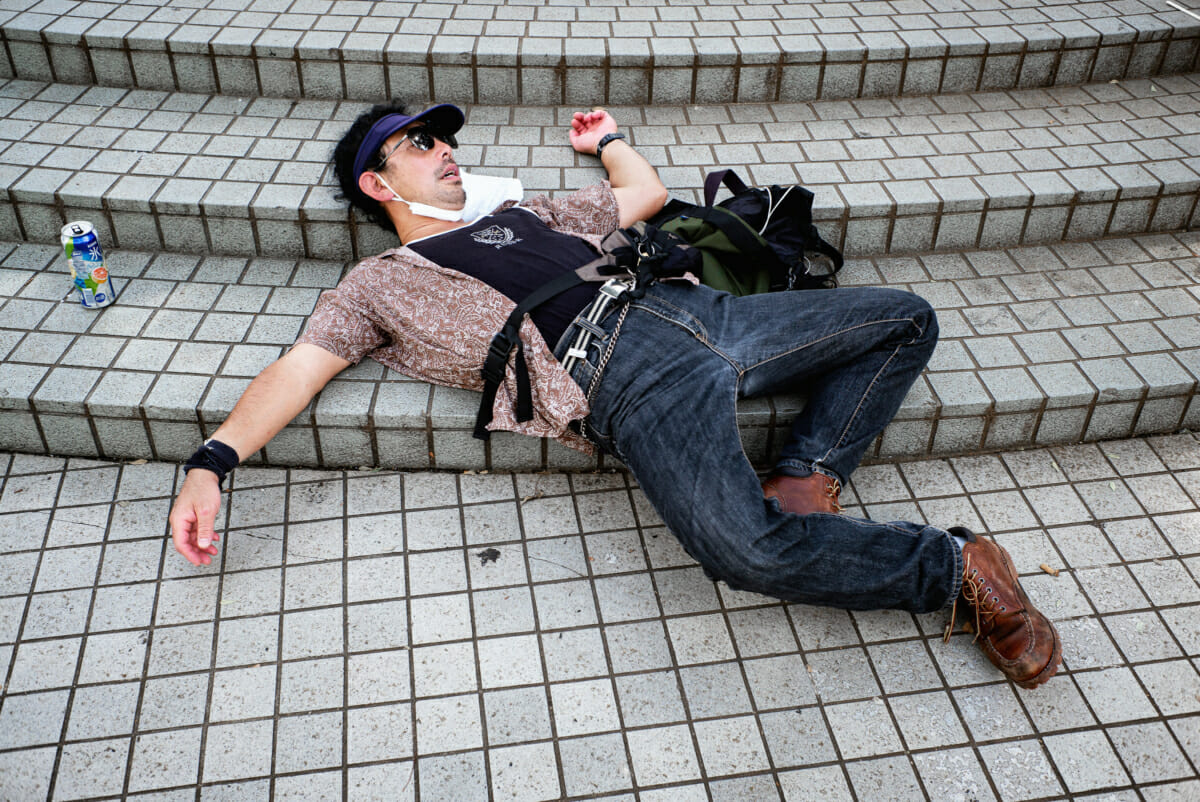 An 80s style Japanese man drunk and asleep on the street